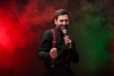 Emotional man with microphone singing in color lights