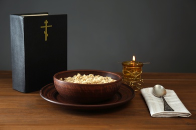 Photo of Bible, oatmeal porridge and spoon on wooden table. Lent season