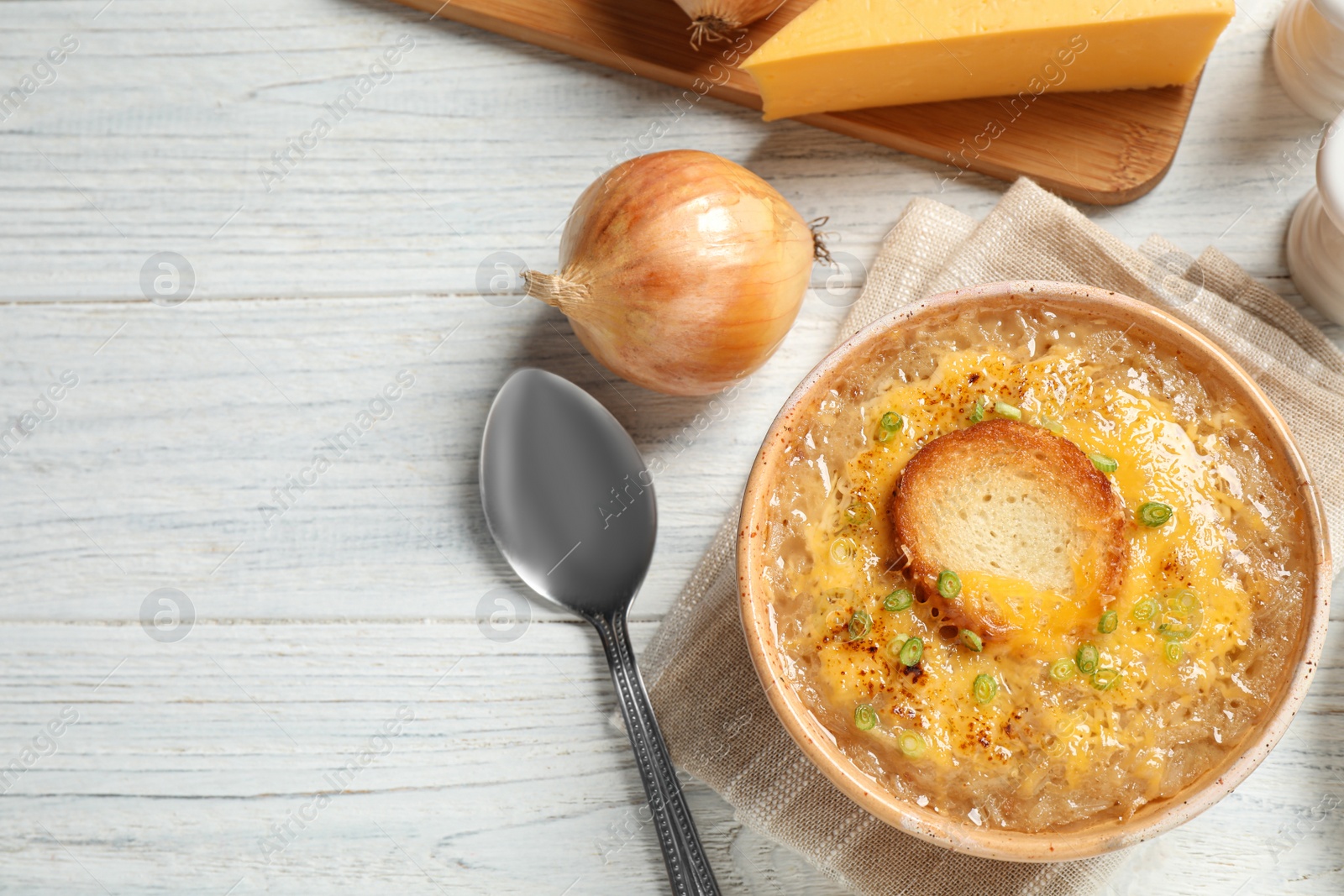 Photo of Tasty homemade french onion soup served on white wooden table, flat lay. Space for text