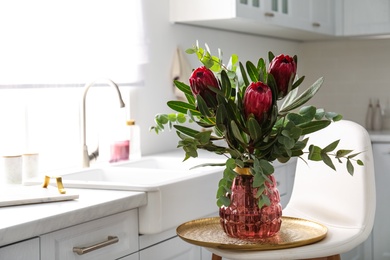 Photo of Bouquet with beautiful protea flowers in kitchen, space for text. Interior design