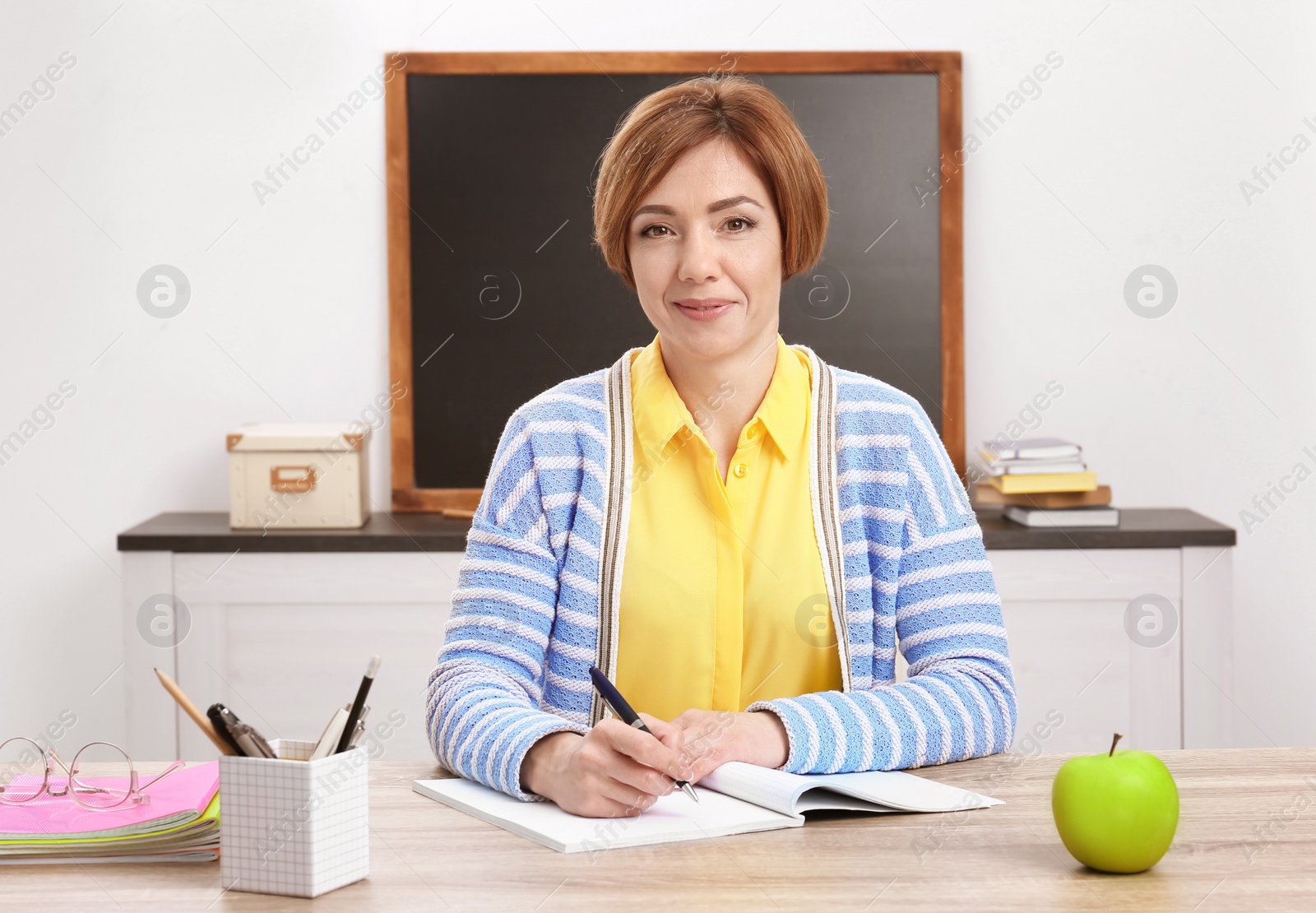 Photo of Portrait of female teacher sitting at table in classroom