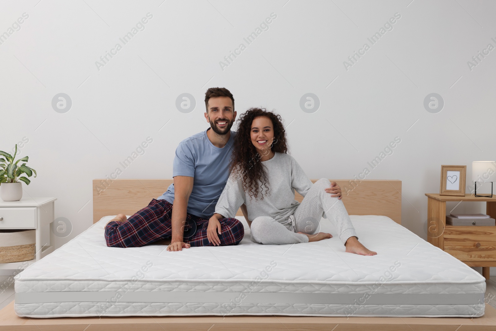 Photo of Happy couple on bed with comfortable mattress at home