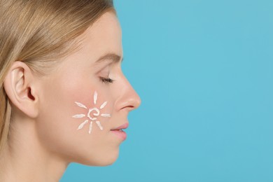 Photo of Beautiful young woman with sun protection cream on her face against light blue background, closeup. Space for text