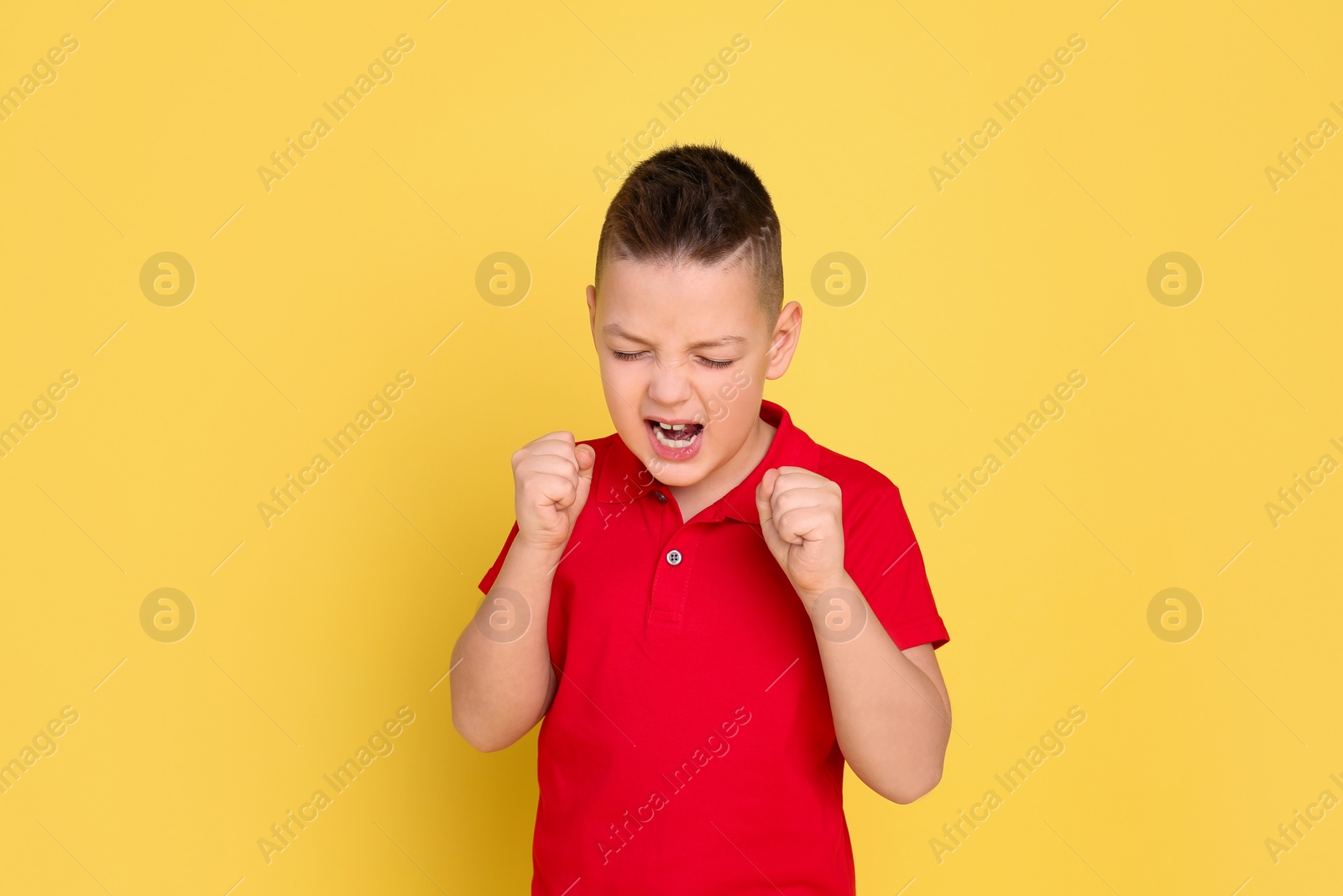 Photo of Portrait of emotional little boy on yellow background