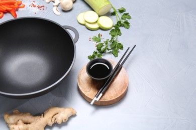 Photo of Wok, chopsticks and different products on grey table, space for text