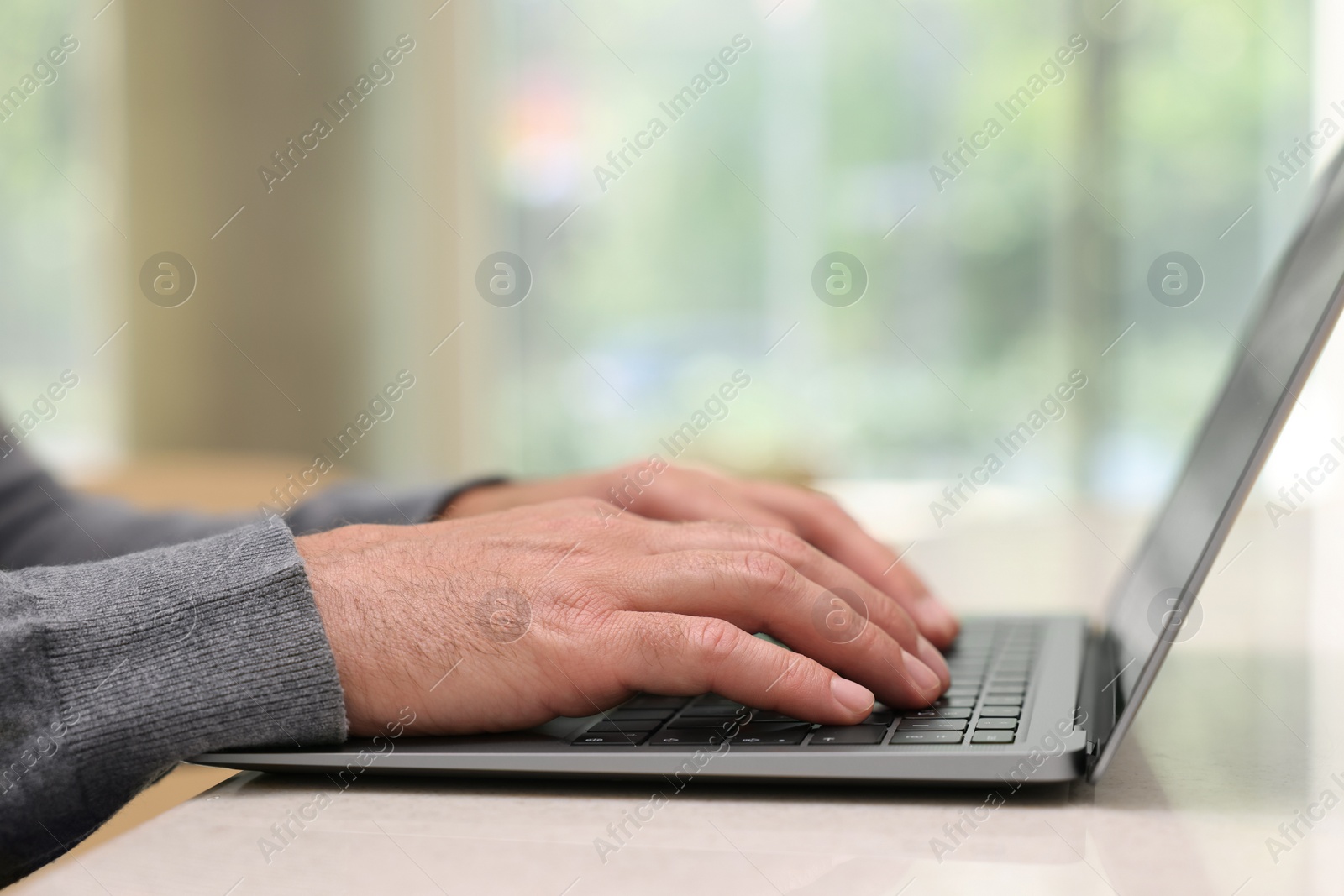 Photo of Man working on laptop at table in cafe, closeup