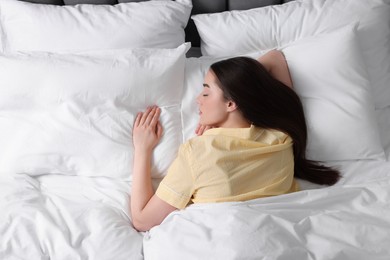 Photo of Beautiful young woman sleeping in soft bed, above view