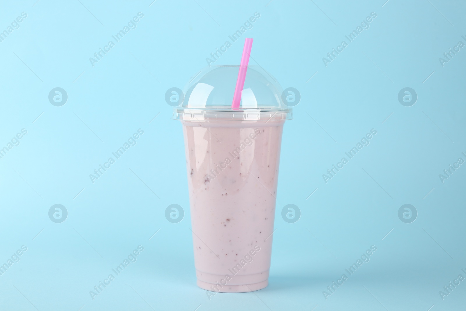 Photo of Plastic cup of tasty smoothie on light blue background