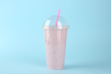 Photo of Plastic cup of tasty smoothie on light blue background