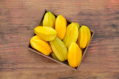 Delicious ripe carambolas in box on wooden table, top view