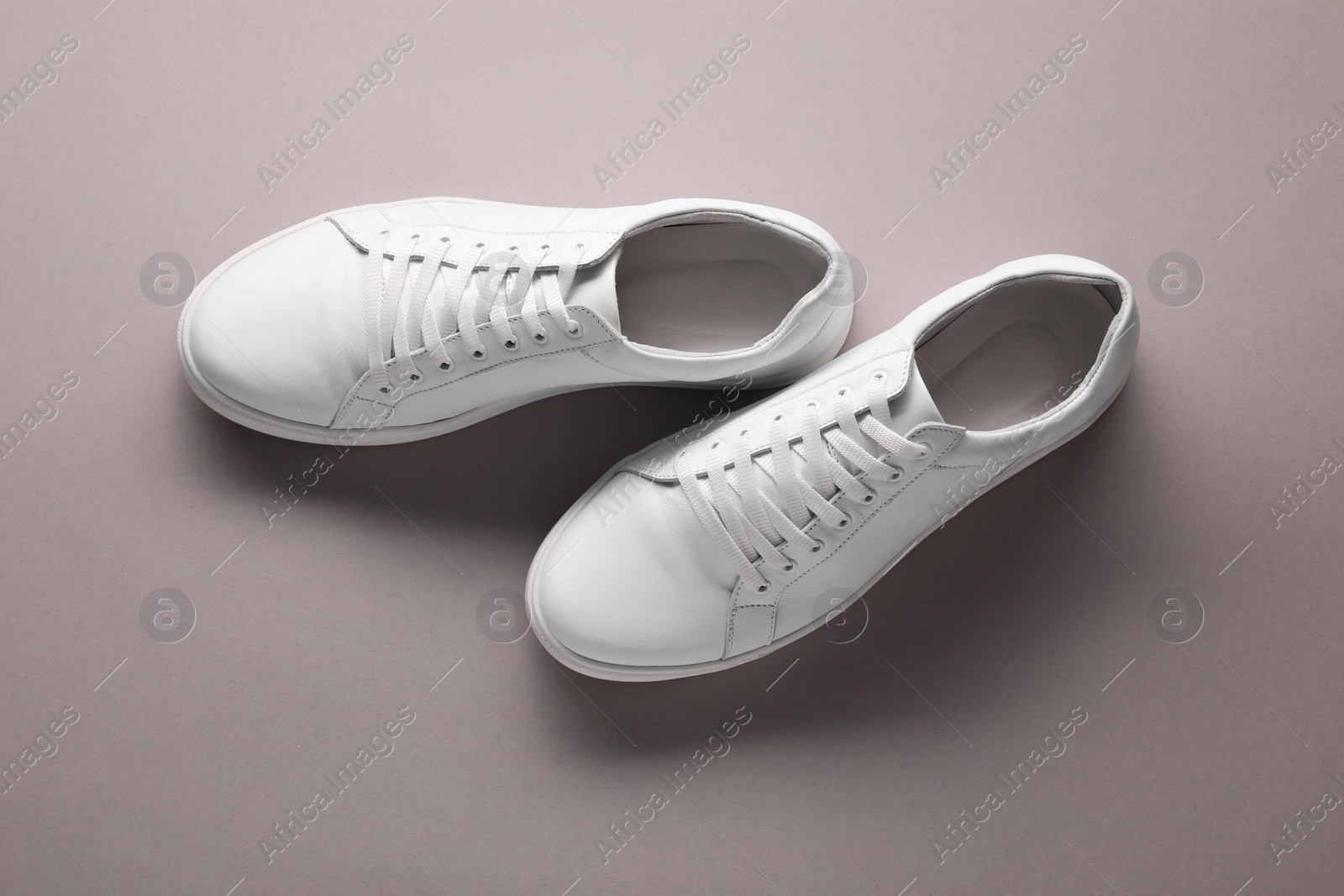 Photo of Pair of stylish white sneakers on grey background, top view