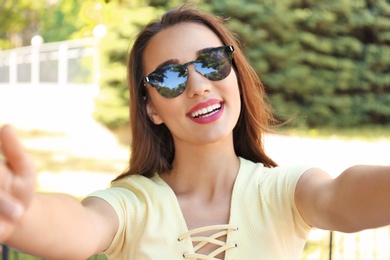 Young woman taking selfie outdoors on sunny day