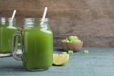 Photo of Fresh celery juice and lemon slice on blue wooden table, closeup. Space for text