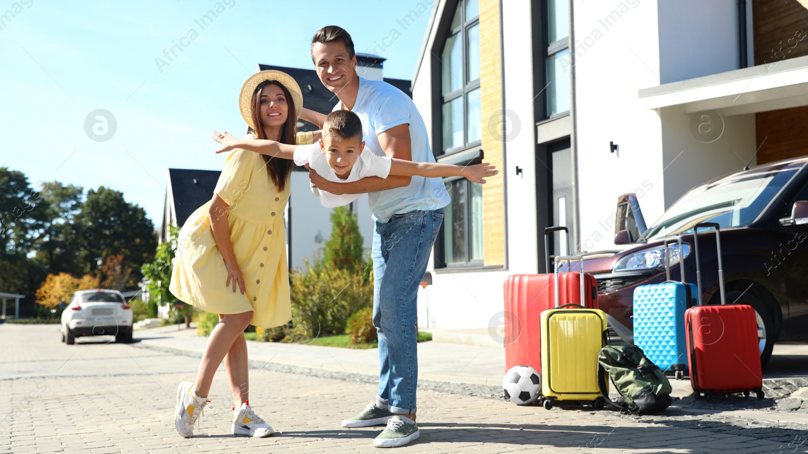 Photo of Happy family with suitcases near house outdoors. Moving day