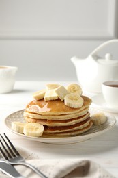 Photo of Delicious pancakes with bananas, honey and butter on white wooden table. Space for text