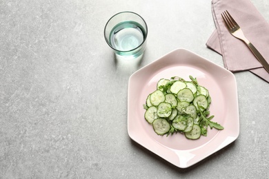 Photo of Plate with delicious cucumber salad served on grey table, top view. Space for text