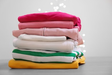 Photo of Stack of folded clothes on wooden table against beige background, space for text