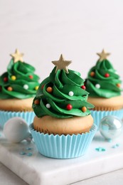 Photo of Christmas tree shaped cupcakes and decor on table