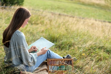Photo of Young woman drawing with soft pastels in nature. Space for text