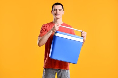 Man with blue cool box on orange background