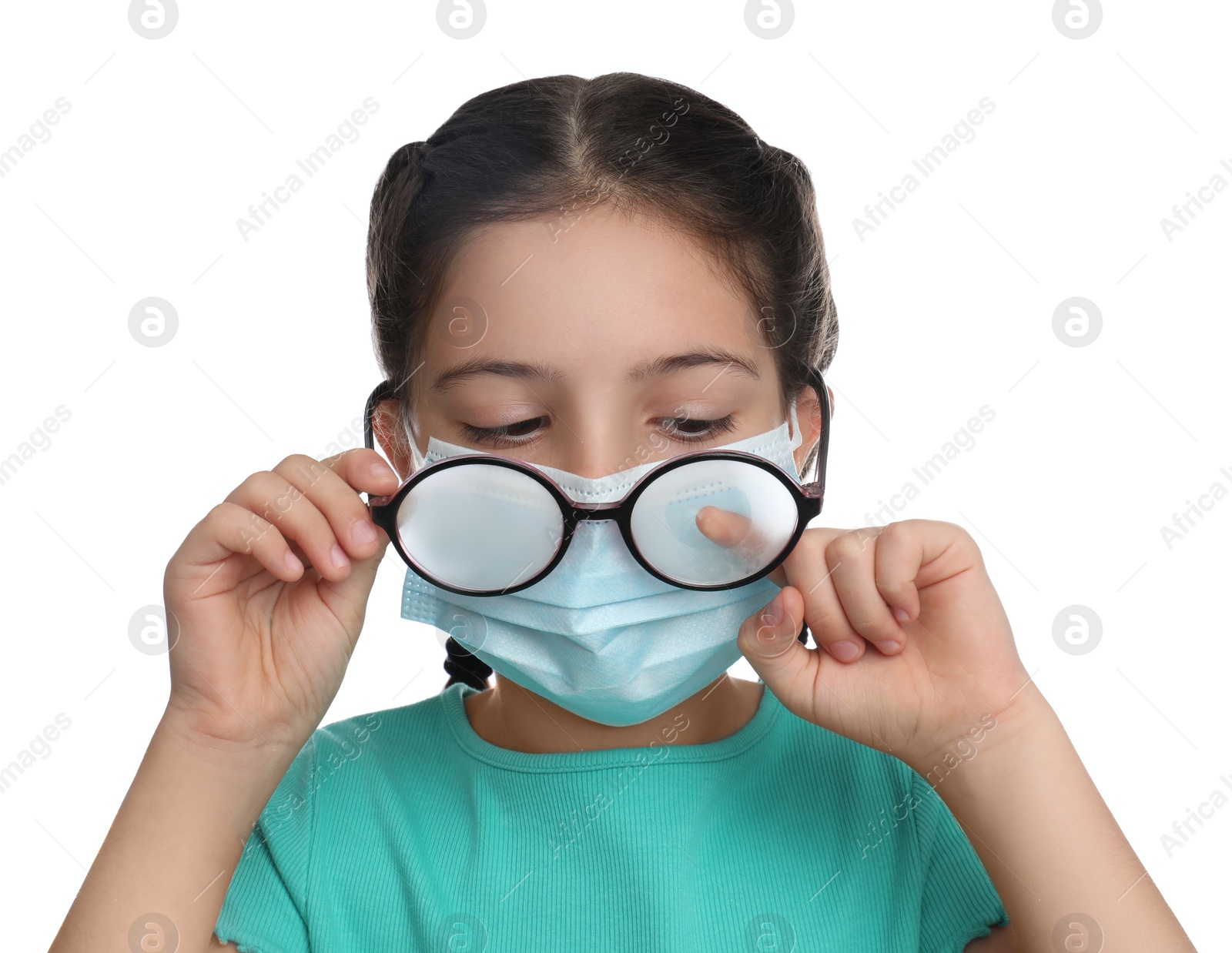 Photo of Little girl wiping foggy glasses caused by wearing medical face mask on white background. Protective measure during coronavirus pandemic