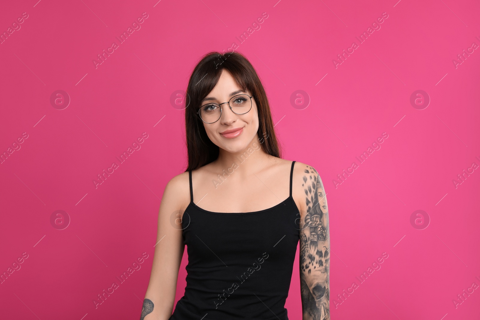 Photo of Woman with tattoos on arms against pink background