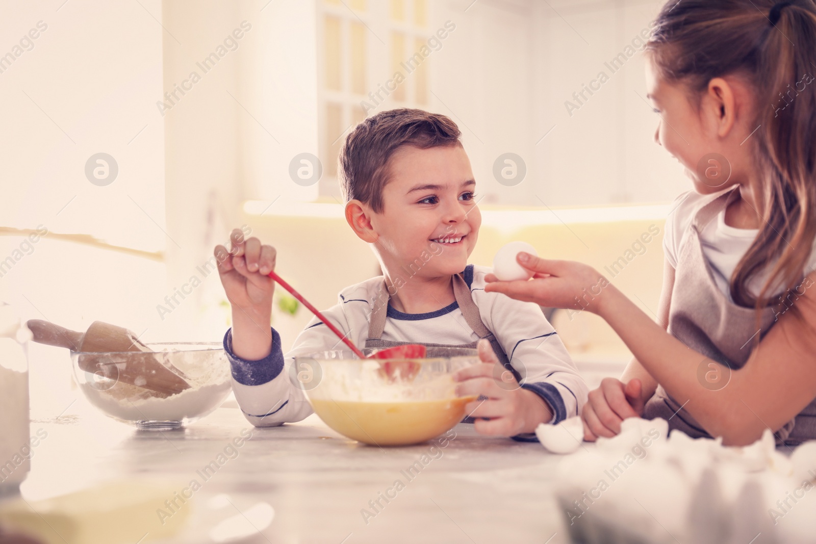 Photo of Cute little children cooking dough together in kitchen