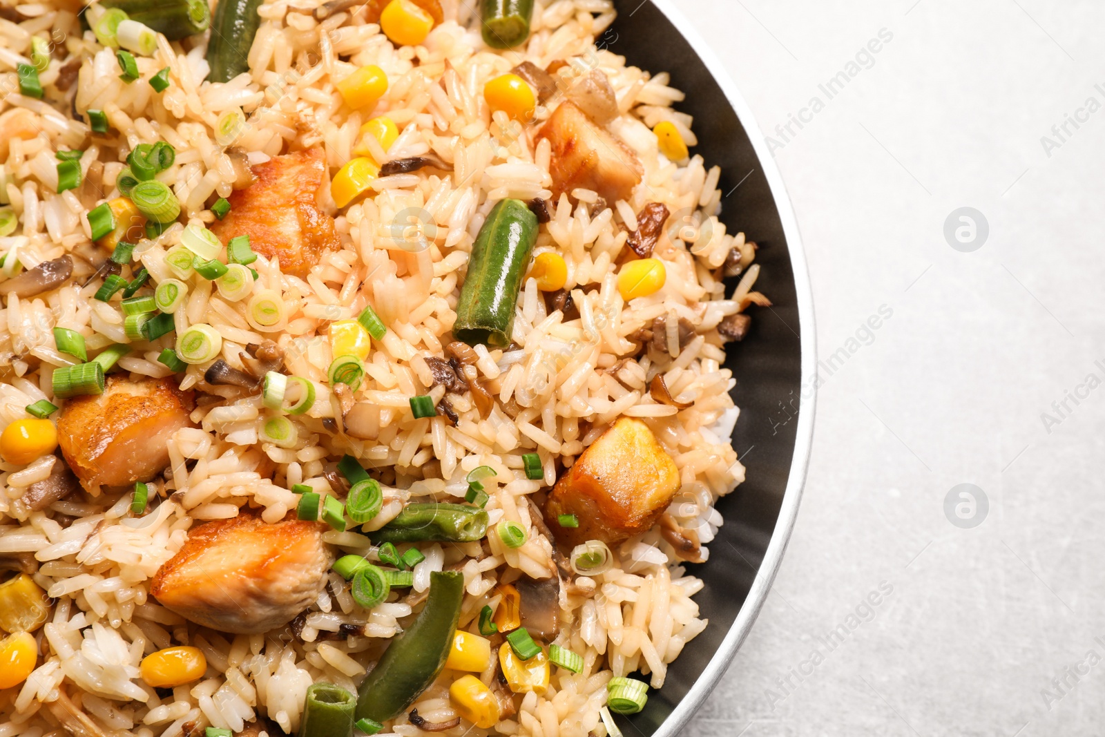 Photo of Delicious rice pilaf with chicken and vegetables on light grey table, closeup