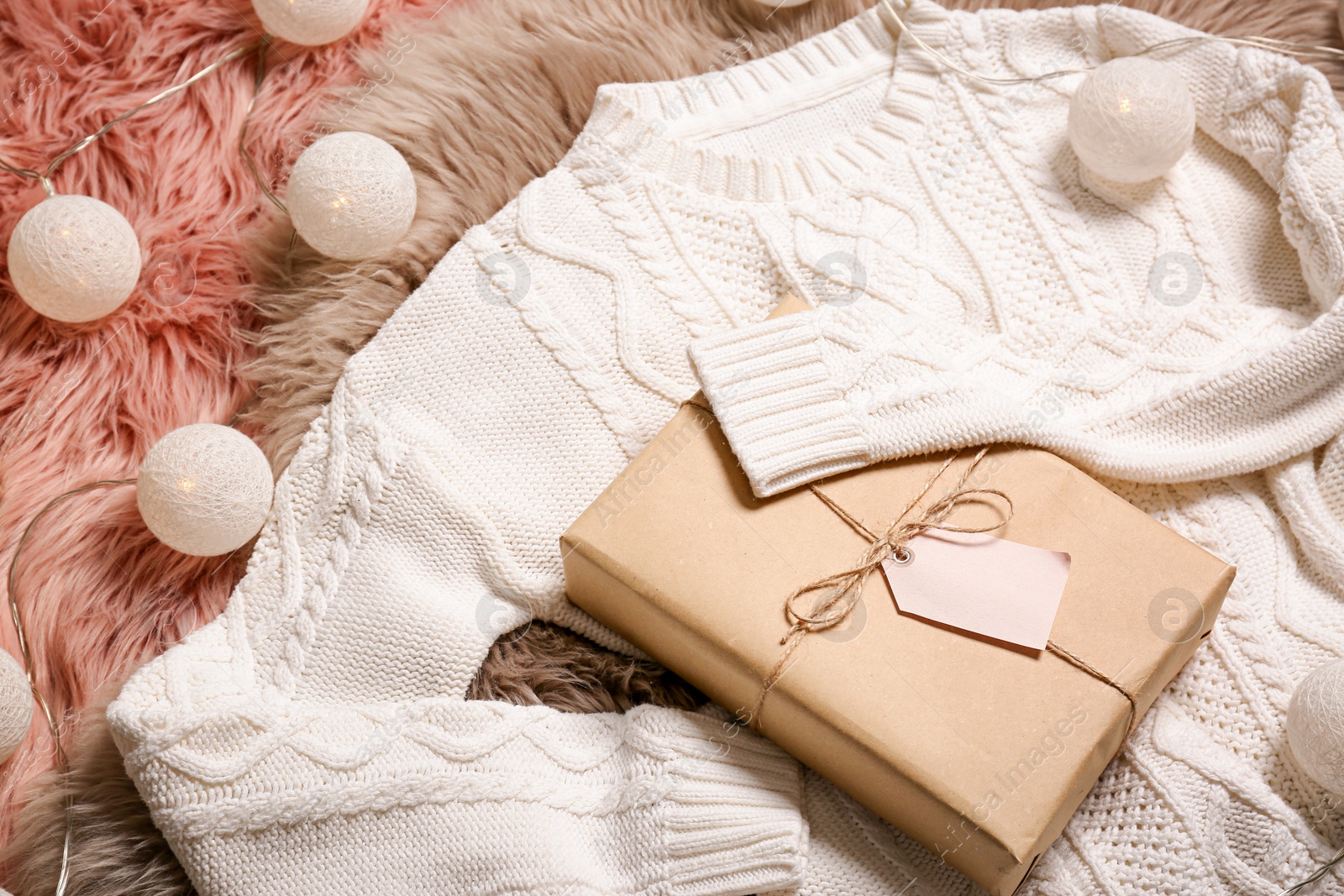 Photo of Composition with warm sweater and package on fur rug