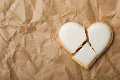 Photo of Broken heart shaped cookie on crumpled paper, top view with space for text. Relationship problems concept