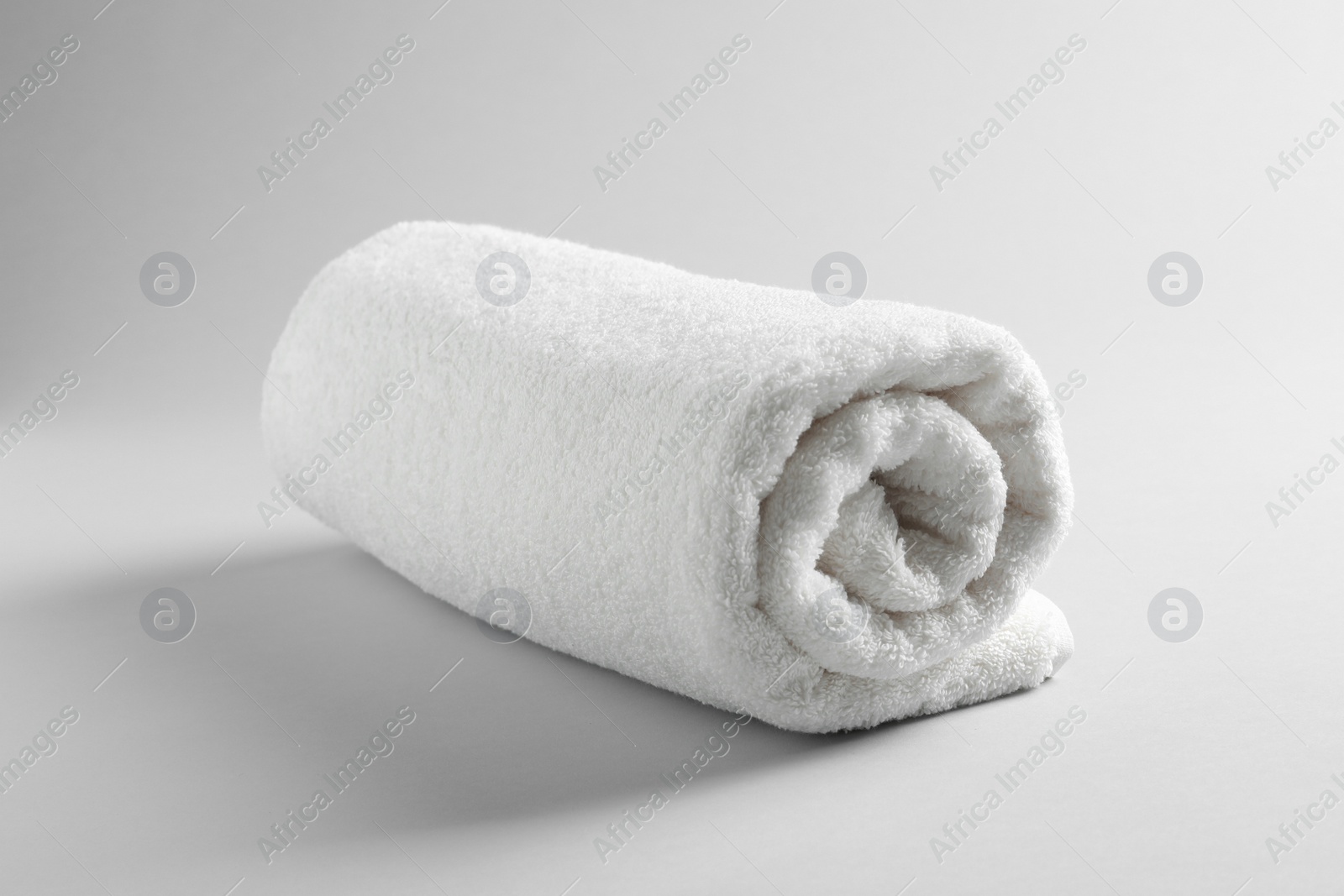 Photo of Fresh soft rolled towel on light background