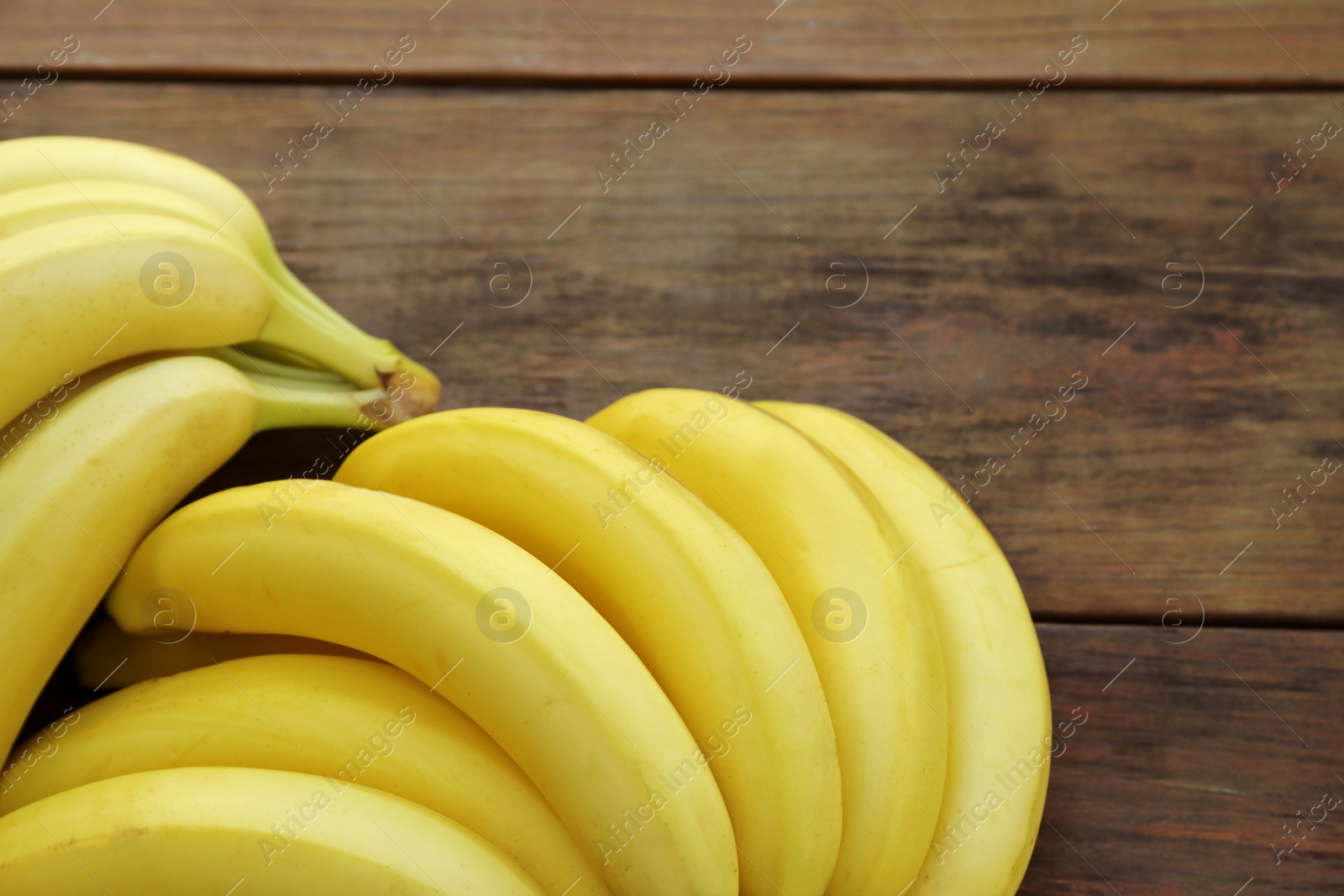 Photo of Ripe yellow bananas on wooden table, closeup. Space for text