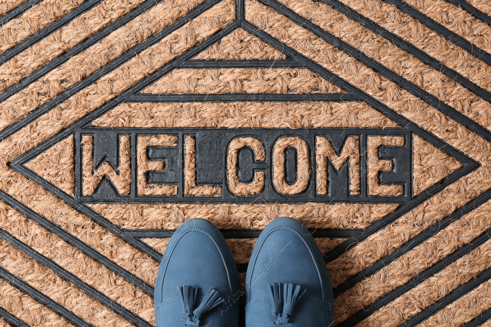 Photo of Blue female shoes on brown welcome doormat, top view