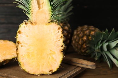 Photo of Cut fresh juicy pineapple on wooden board, closeup