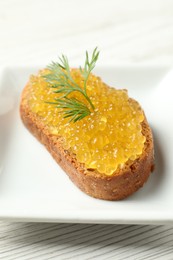 Slice of bread with pike caviar on white wooden table, closeup