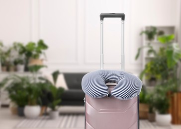 Image of Travel pillow on suitcase in room. Space for text