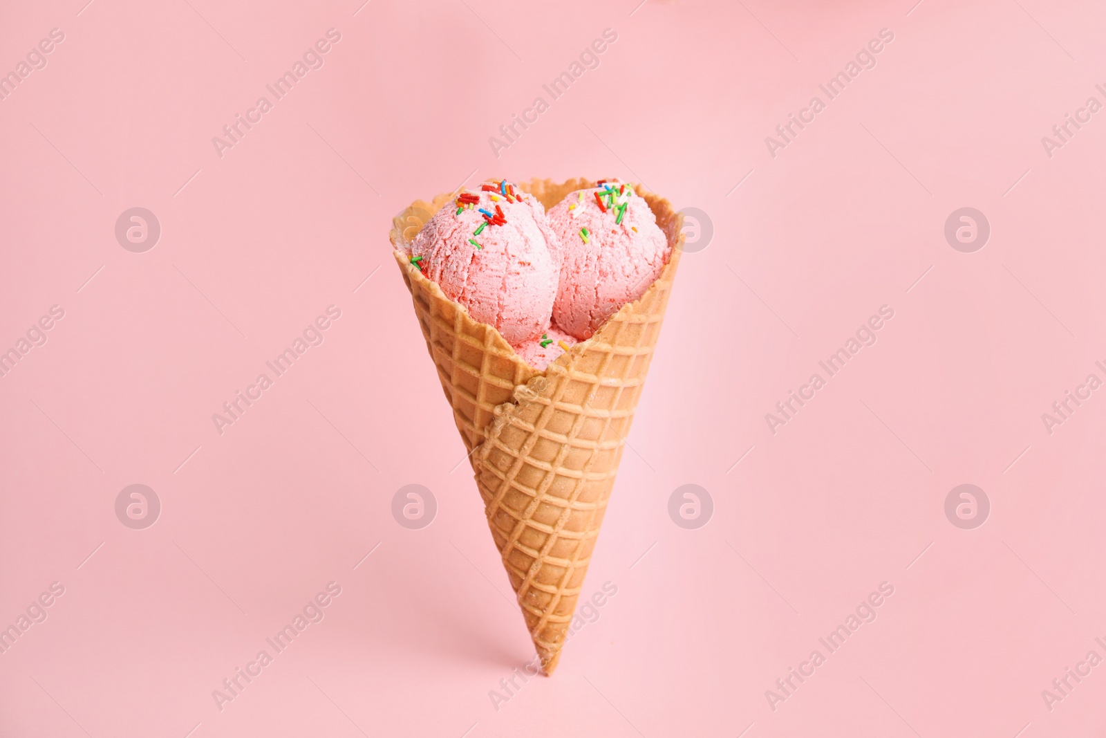 Photo of Delicious ice cream in wafer cone on pink background