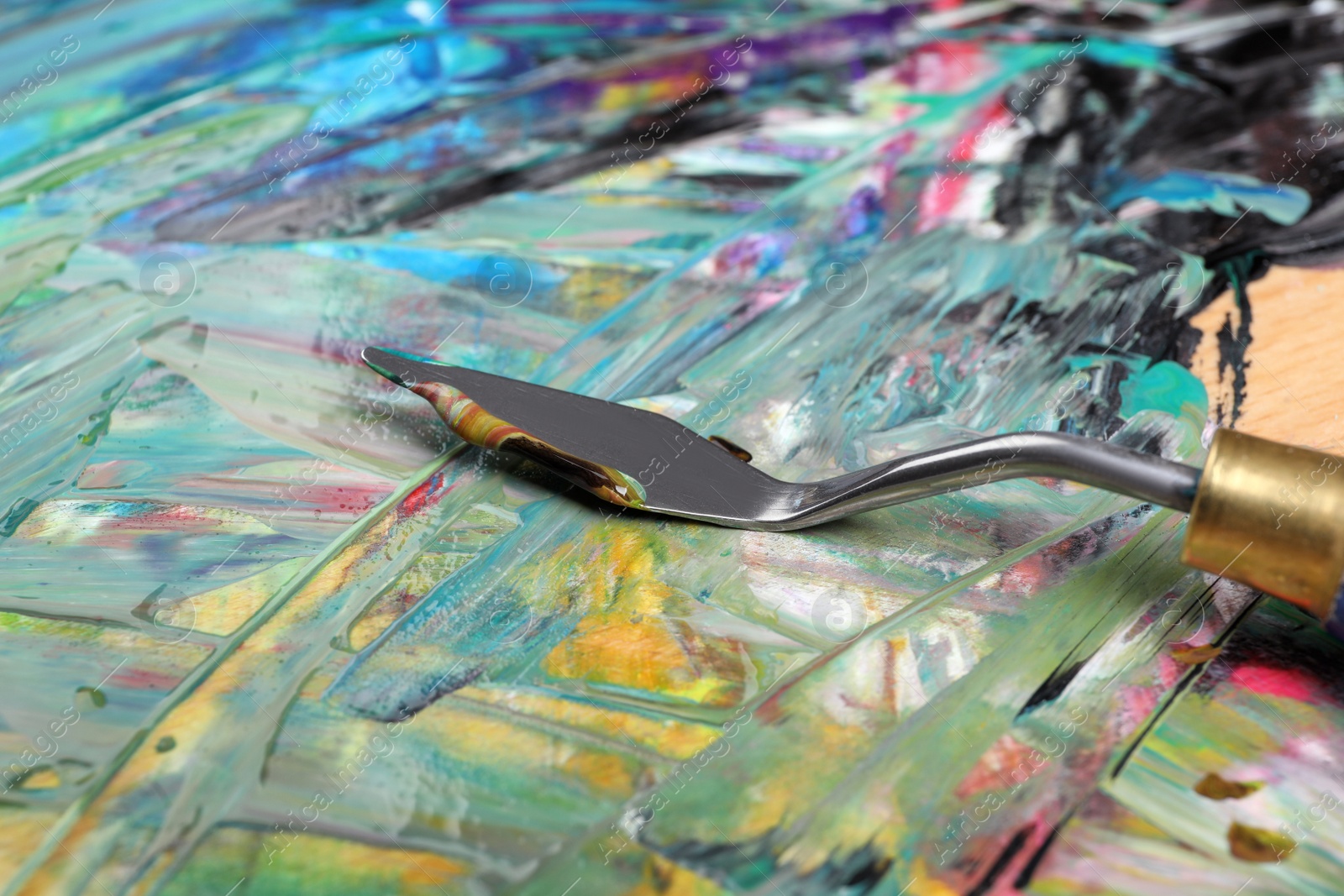 Photo of Abstract colorful acrylic paint and spatula, closeup view