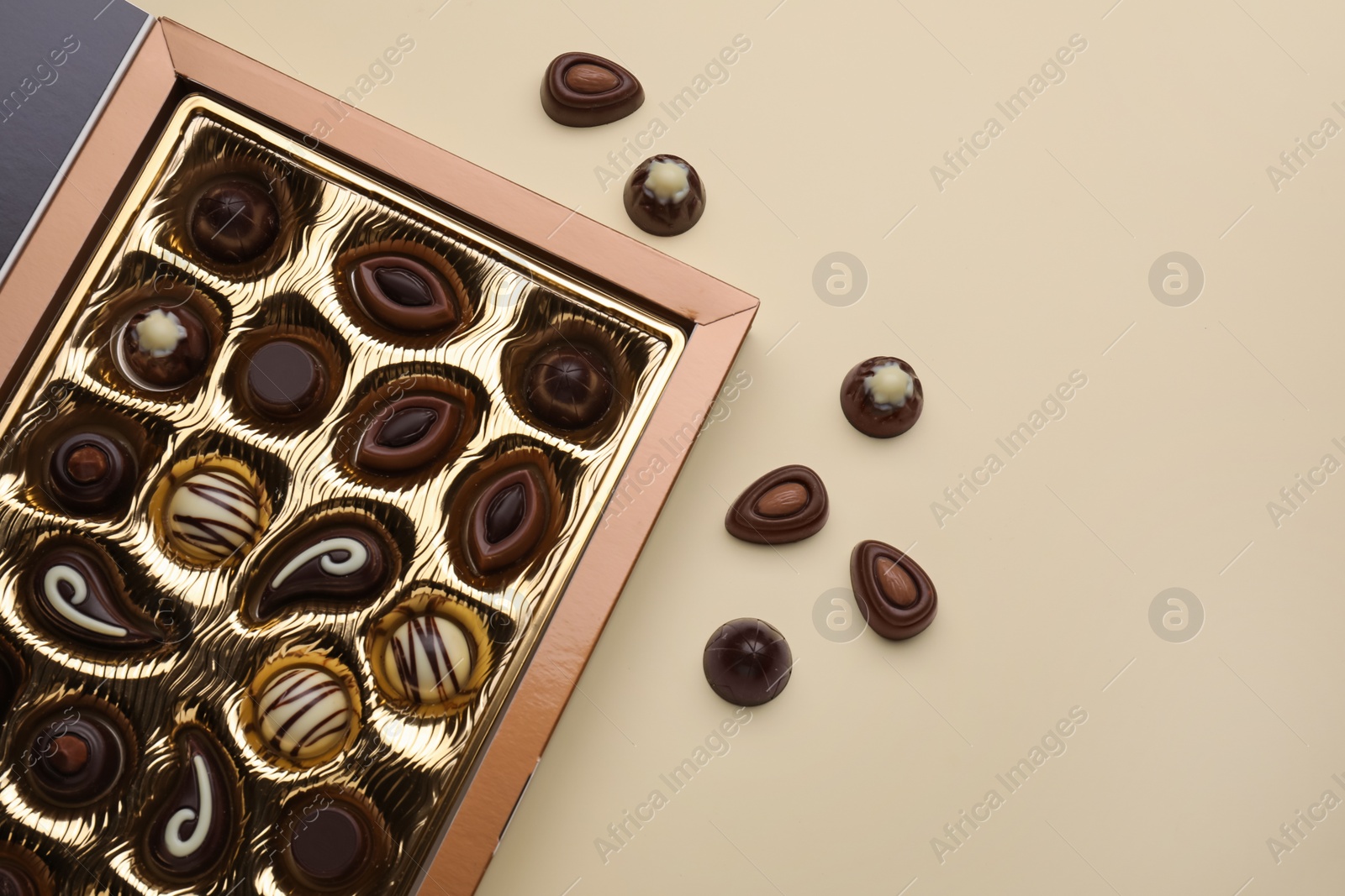 Photo of Box of delicious chocolate candies on beige background, flat lay. Space for text