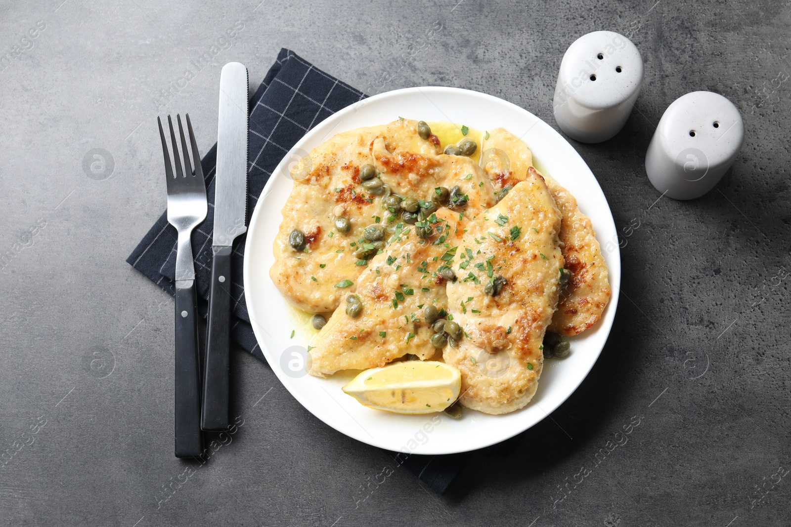 Photo of Delicious chicken piccata with herbs served on grey table, flat lay