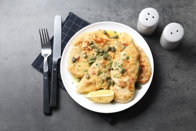 Delicious chicken piccata with herbs served on grey table, flat lay