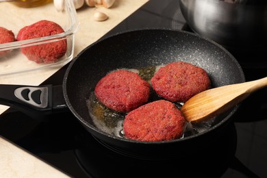 Cooking vegan cutlets in frying pan on stove, closeup