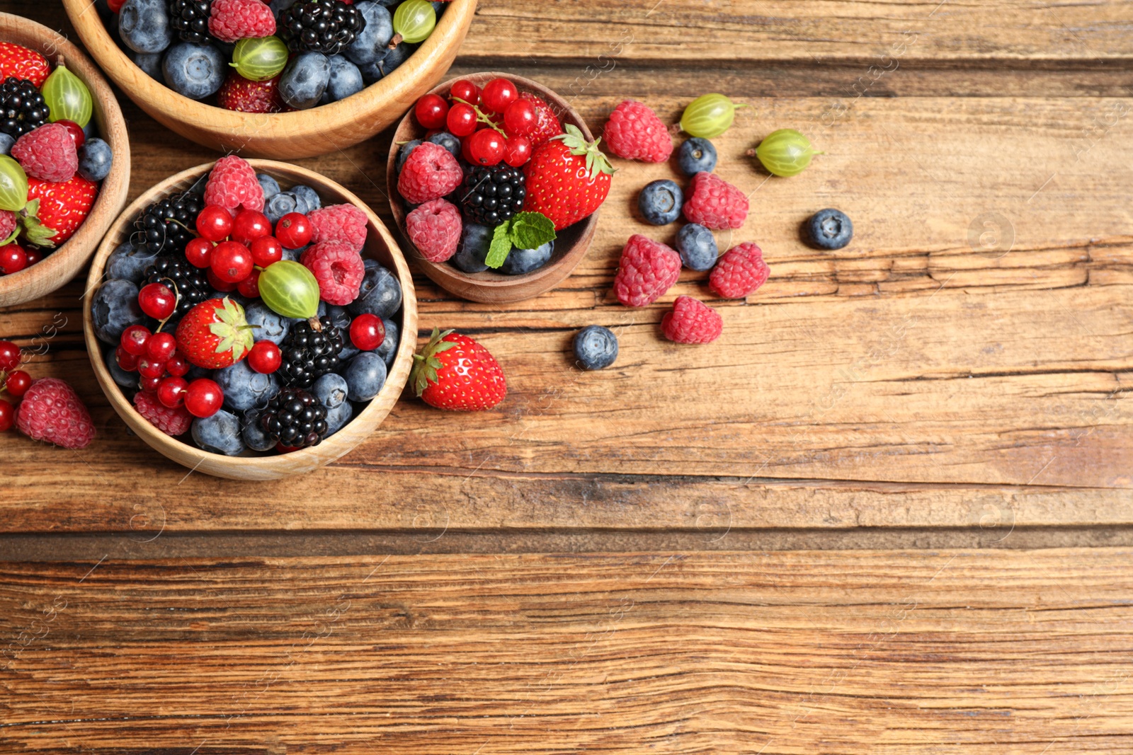 Photo of Mix of ripe berries on wooden table, flat lay. Space for text