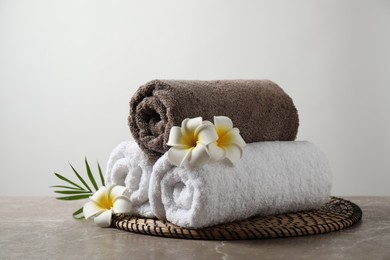 Beautiful spa composition with plumeria flowers on grey marble table against light background