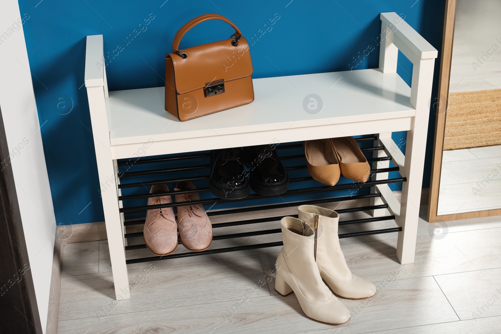 Photo of Shoe storage bench near blue wall in hallway. Interior design