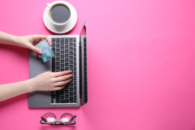 Photo of Online payment. Woman with laptop, credit card, glasses and coffee on pink background, top view. Space for text