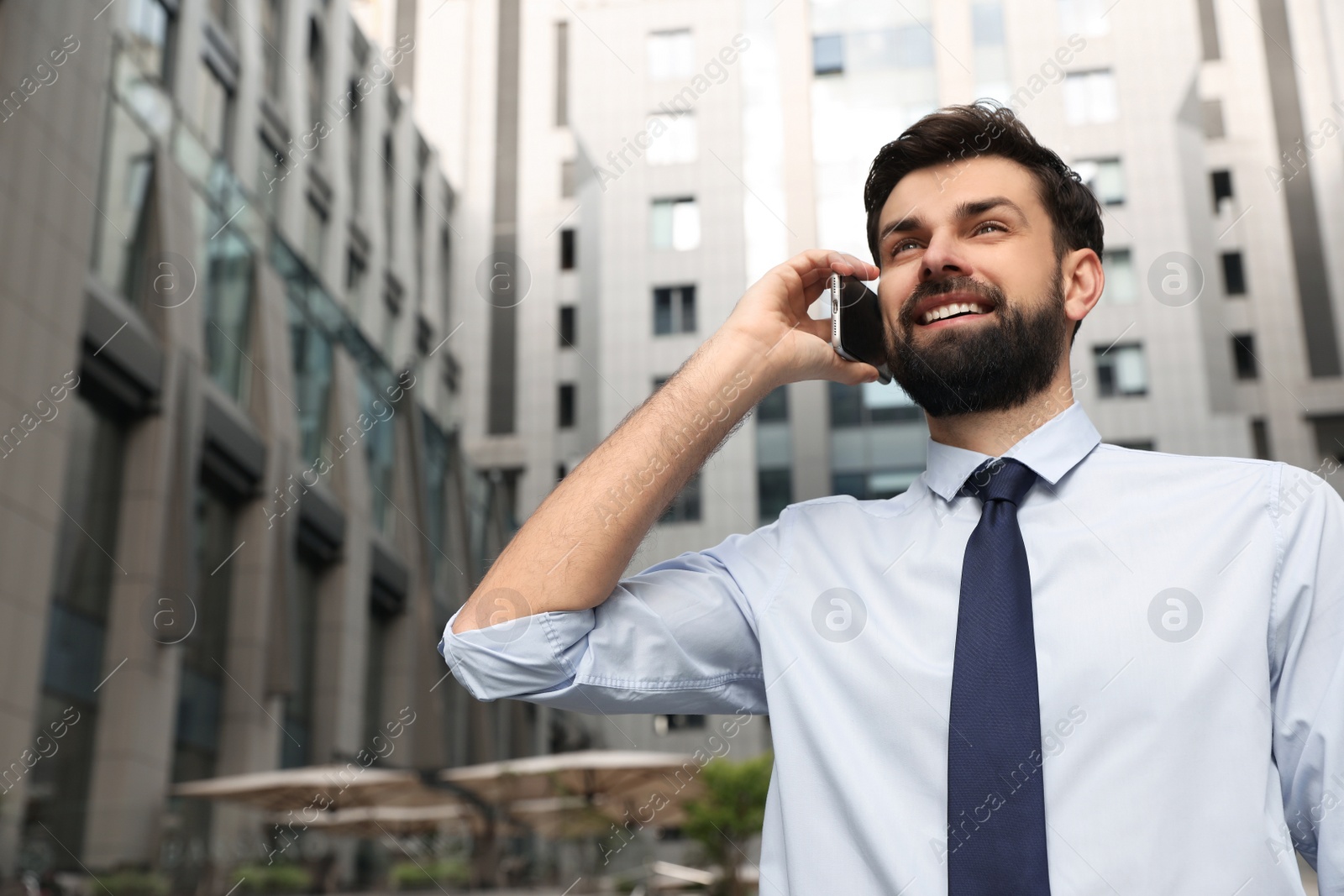 Photo of Handsome man talking on phone in modern city