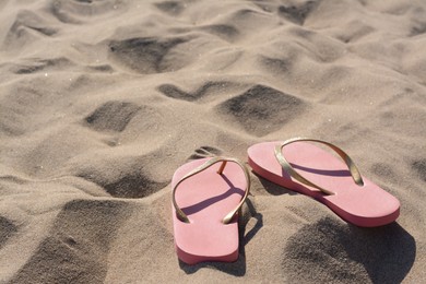 Photo of Stylish pink flip flops on sandy beach, space for text