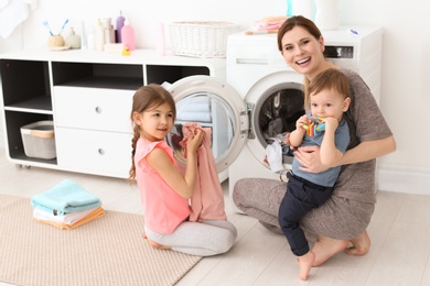 Housewife with little children doing laundry at home