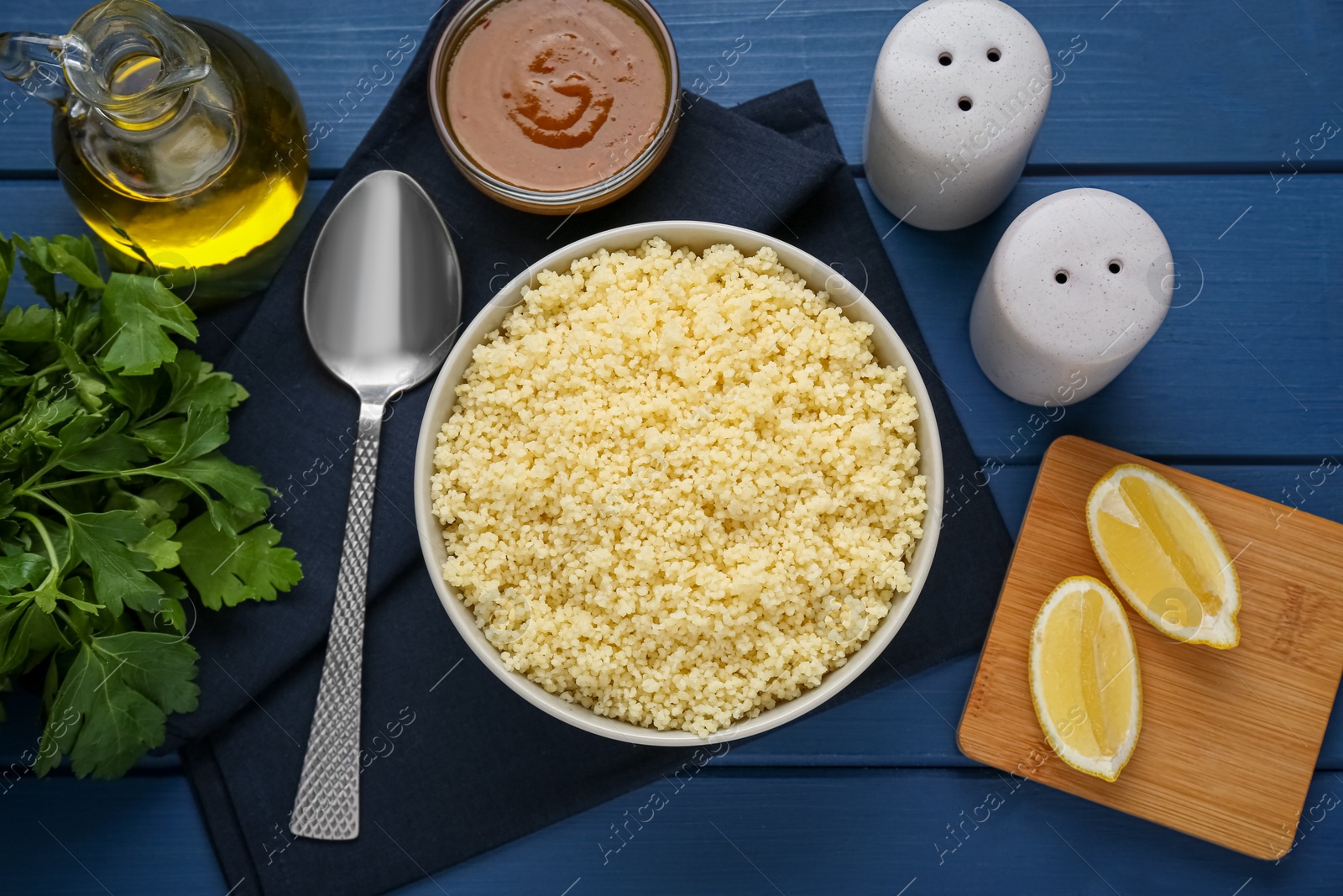 Photo of Tasty couscous and ingredients on blue wooden table, flat lay